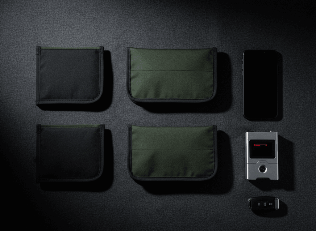 Faraday bags and signal-blocking phone sleeves next to a phone and a car key fob